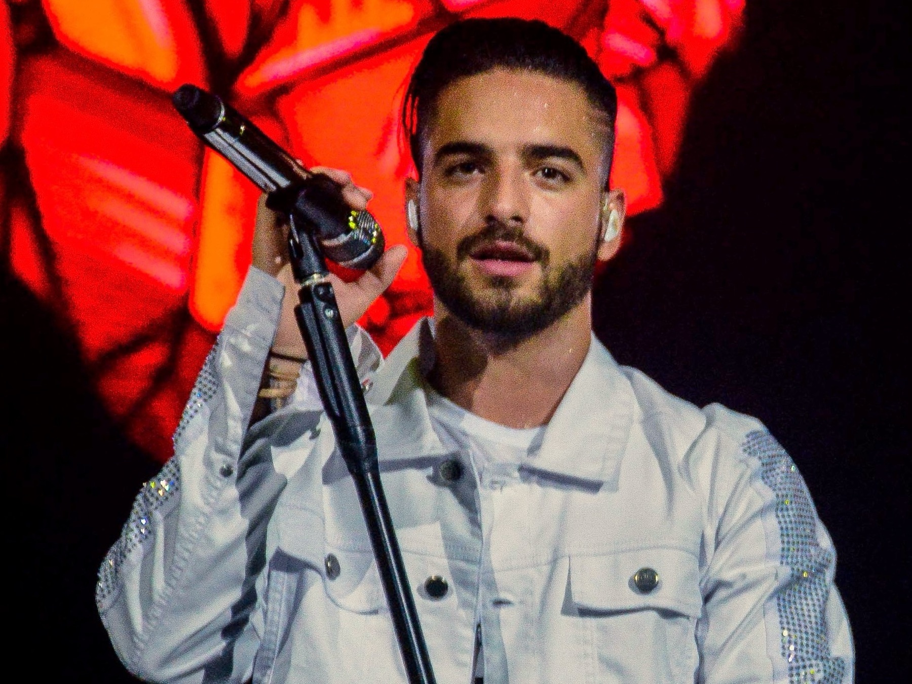 Maluma cantando en un escenario, con micrófono