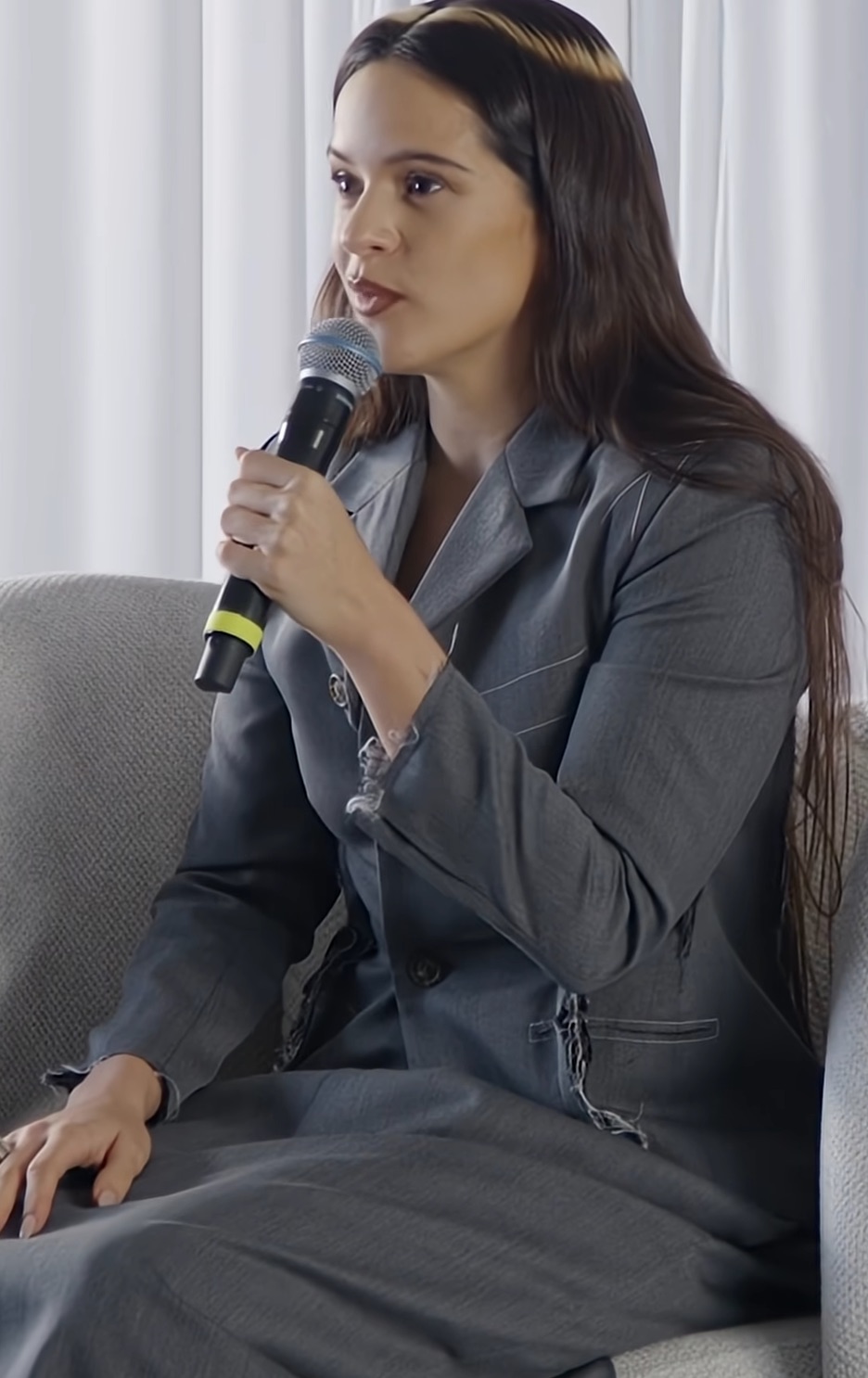 Rosalía, sentada, con micrófono