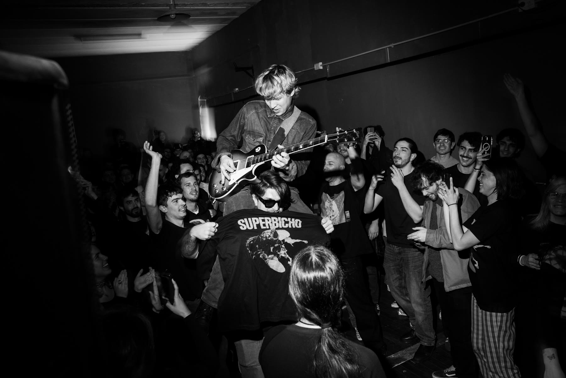 Superbicho tocando, el público cerca, una remera con el nombre de la banda